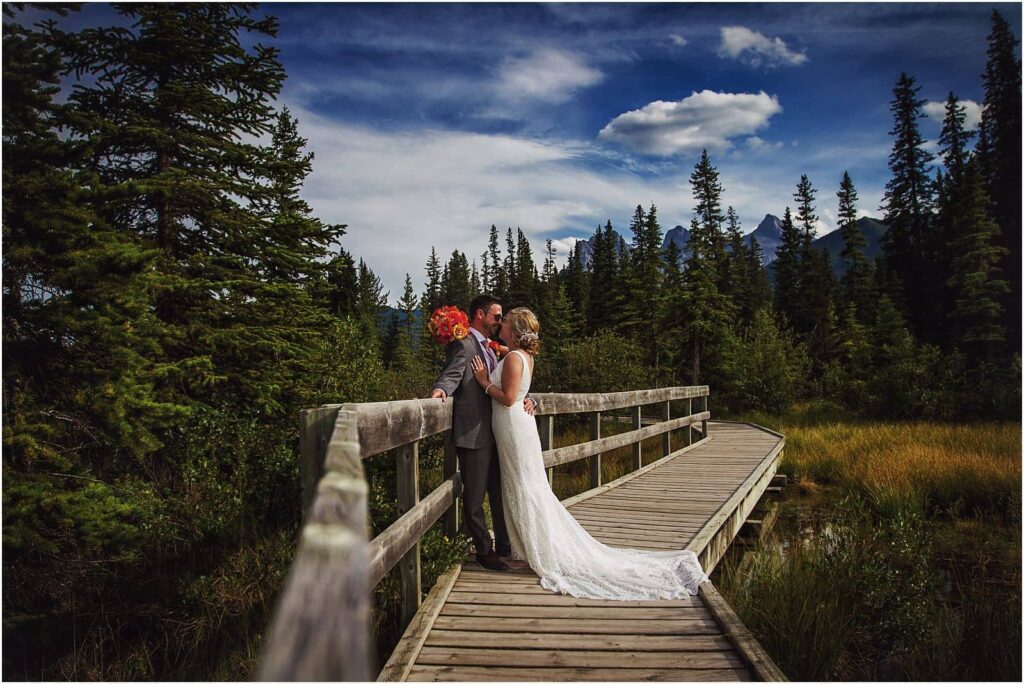 bride and groom in an embrace on a boardwalk leading through a marsh in the mountains - elope in your dream location
