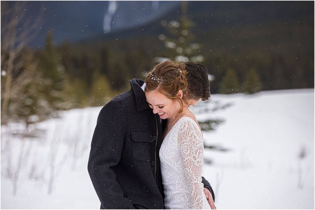 A winter embrace between a bride and groom with snow softly falling all around them