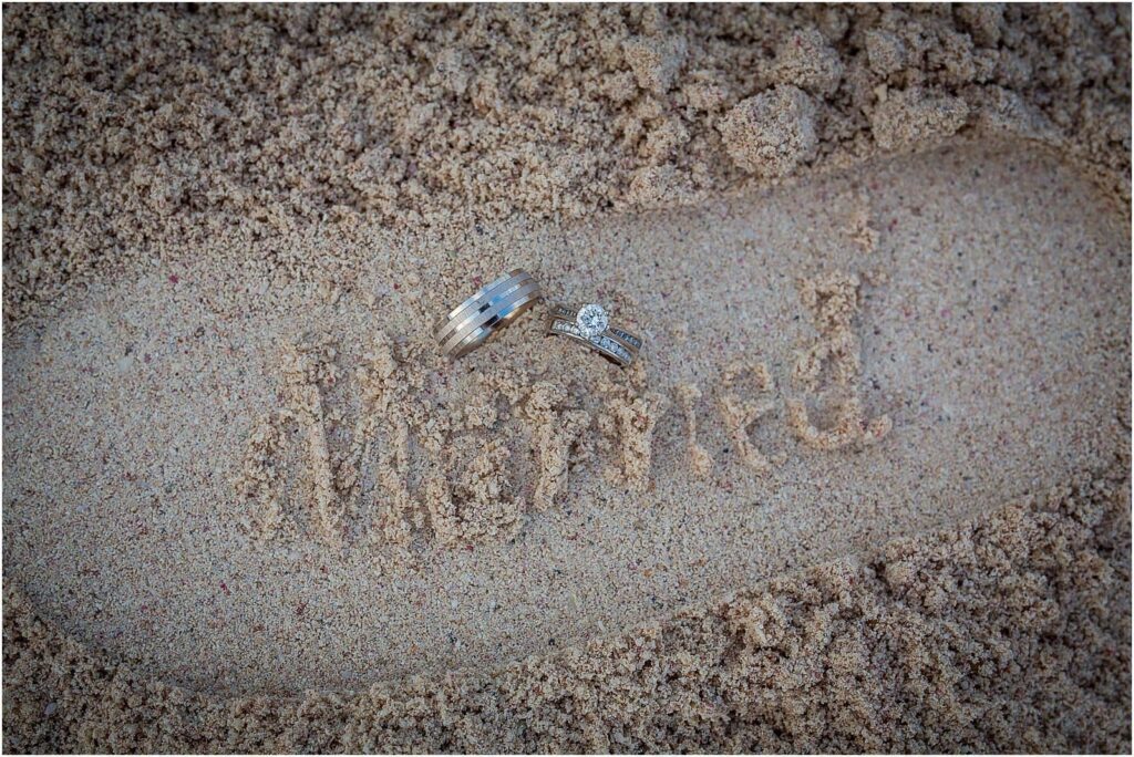 WEDDINGS RINGS IN THE SAND WITH THE WORD MARRIED STAMPED IN THE SAND BY A FLIP FLOP IMPRESSION - elope in your dream location
