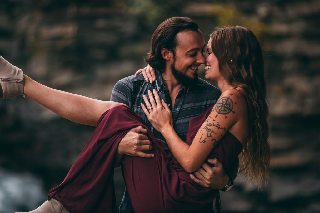 A sweet adventurous engagement photo of a man carrying his partner in his arms