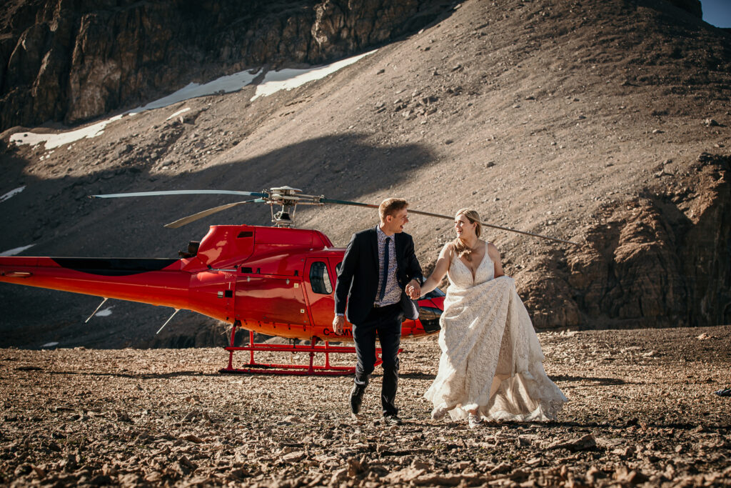 A happy couple in front of a helicopter for their Alberta Helicopter Elopement