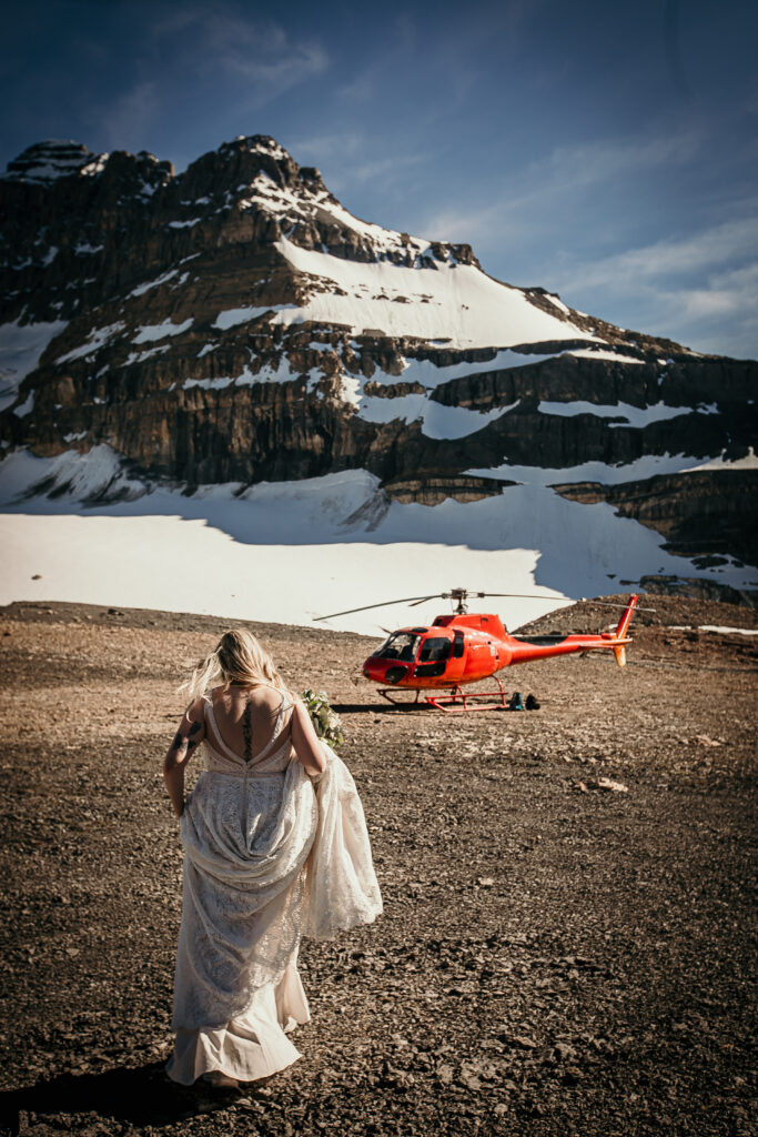 Bride walking towards the helicopter, holding her beautiful white wedding dress