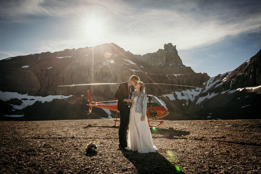 A happy couple in front of a helicopter for their Alberta Helicopter Elopement