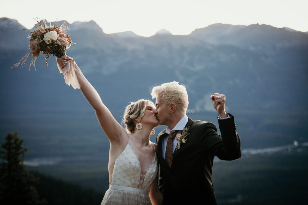 Happy bride and groom kissing photo, with the Canadian Rockies in the backdrop