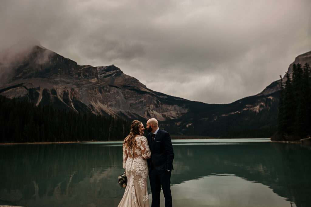 romantic bride and groom photo in Alberta by a lake with the mountains in the backdrop