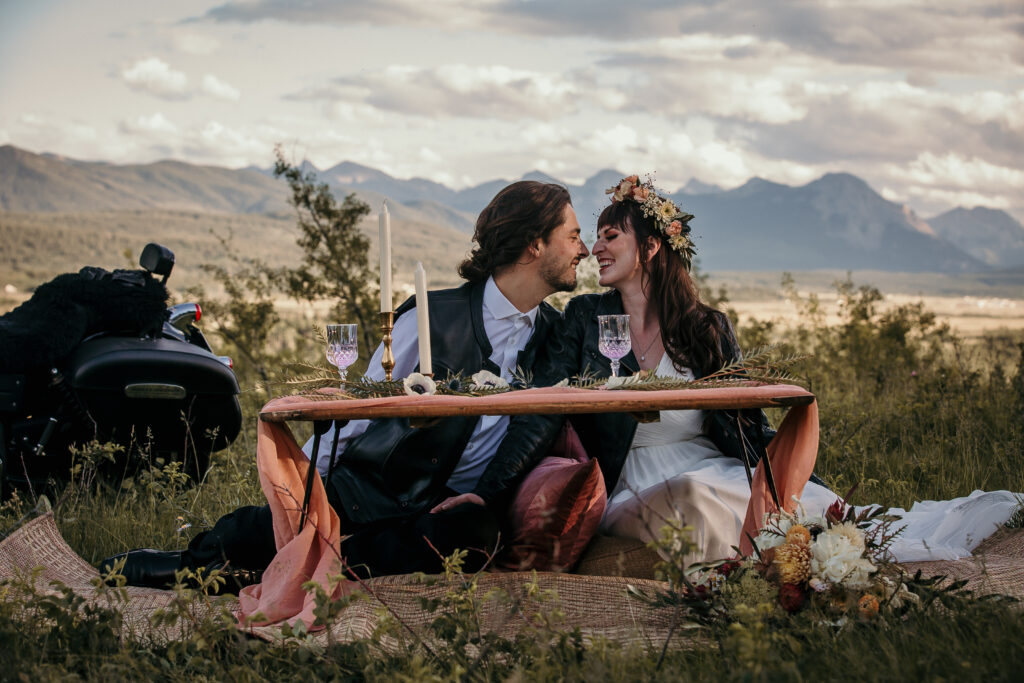 romantic bride and groom alberta elopement photo by a small picnic table with canadian rockies in the backdrop