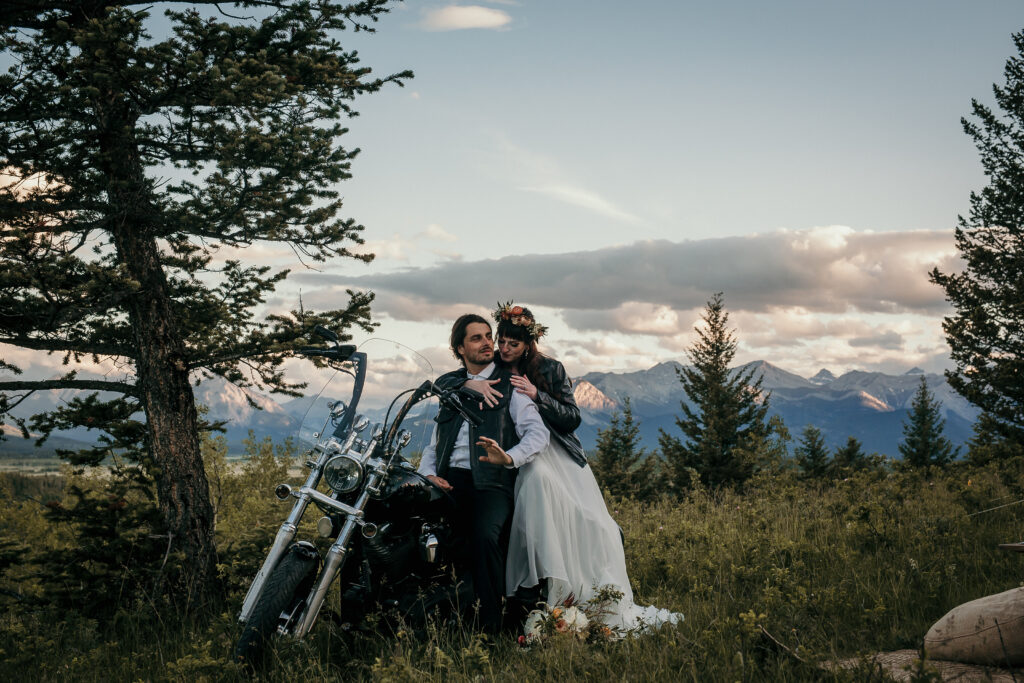 romantic bride and groom alberta elopement photo on a motorcycle with canadian rockies in the backdrop