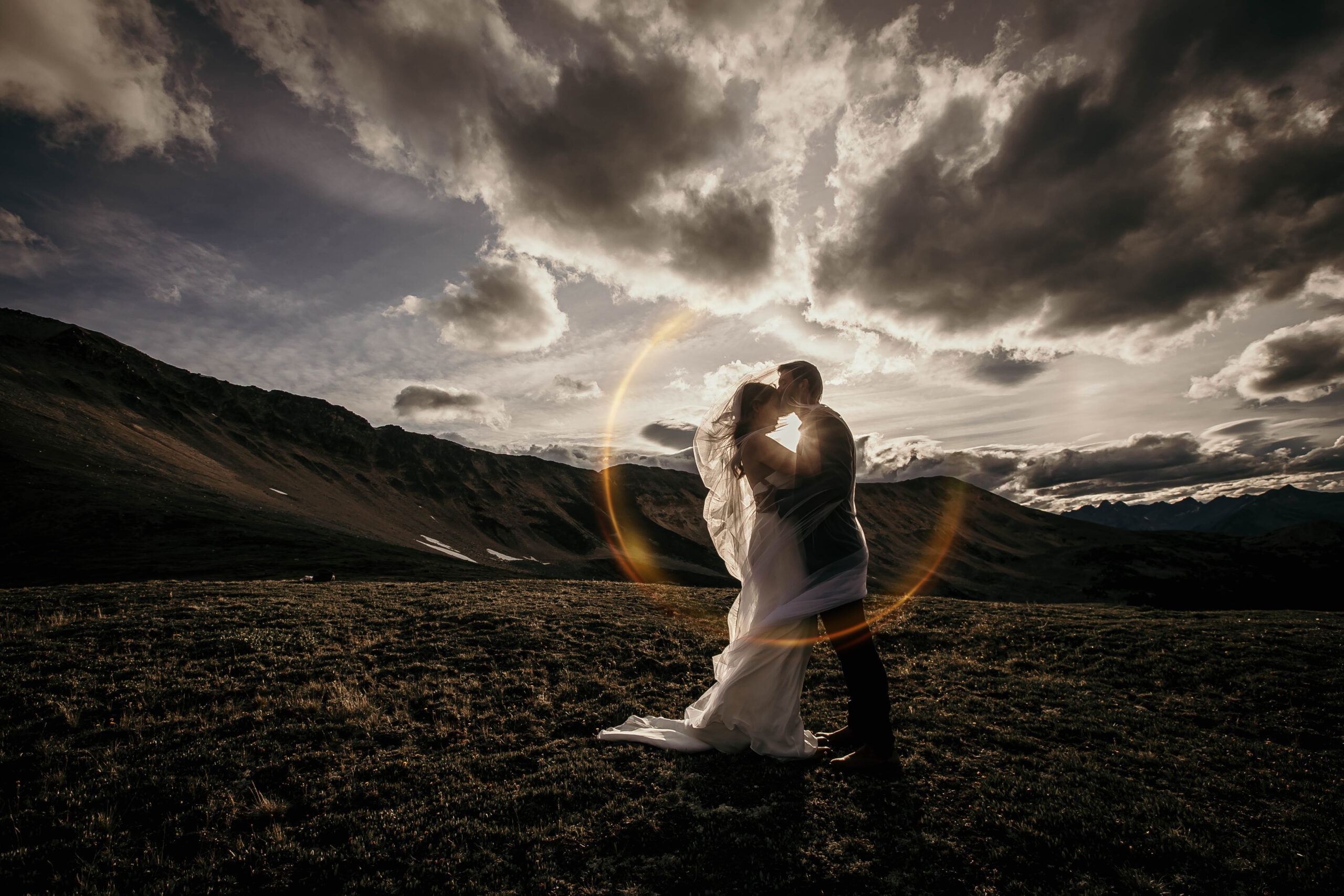 Couple exchanging vows on a mountaintop at sunset in the Alberta Rockies, adventure elopement with golden light and dramatic mountain scenery.