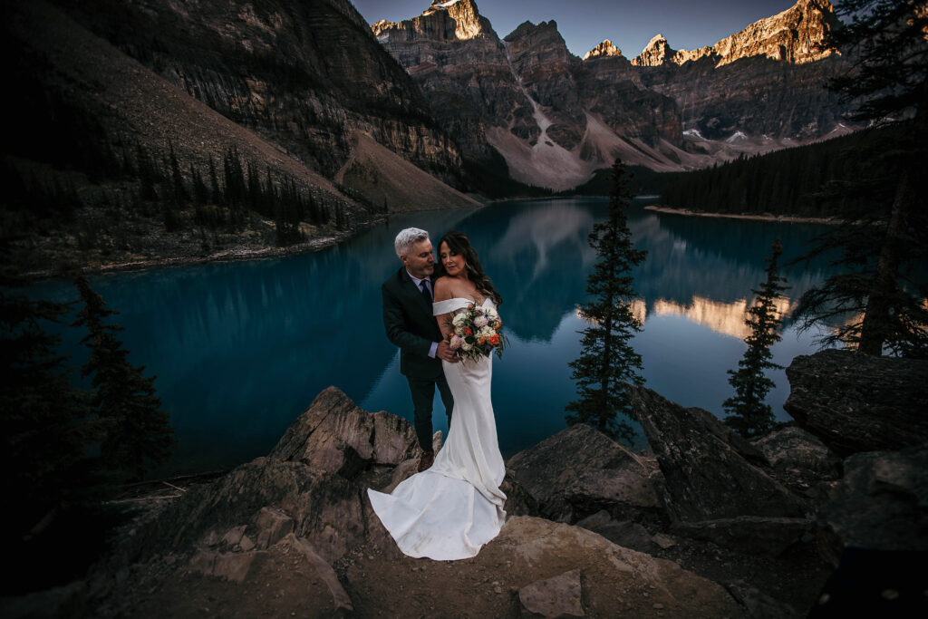 Couple exchanging vows at sunrise at Moraine Lake surrounded by the Valley of the Ten Peaks.