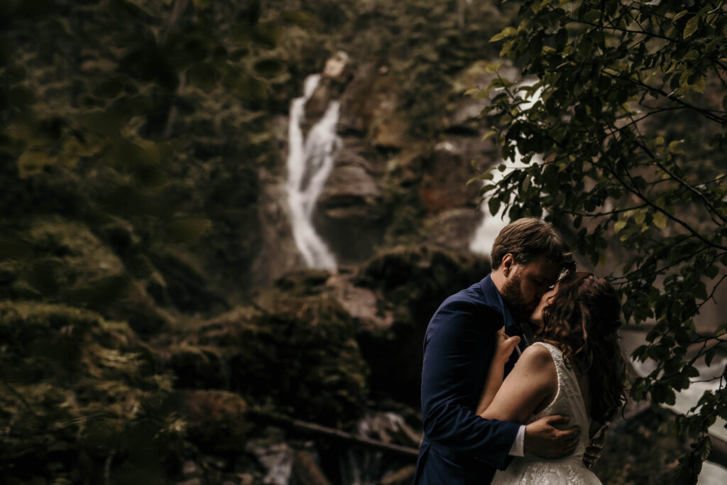 Couple eloping at Begbie Falls near Revelstoke, surrounded by lush forest and cascading waterfall scenery.