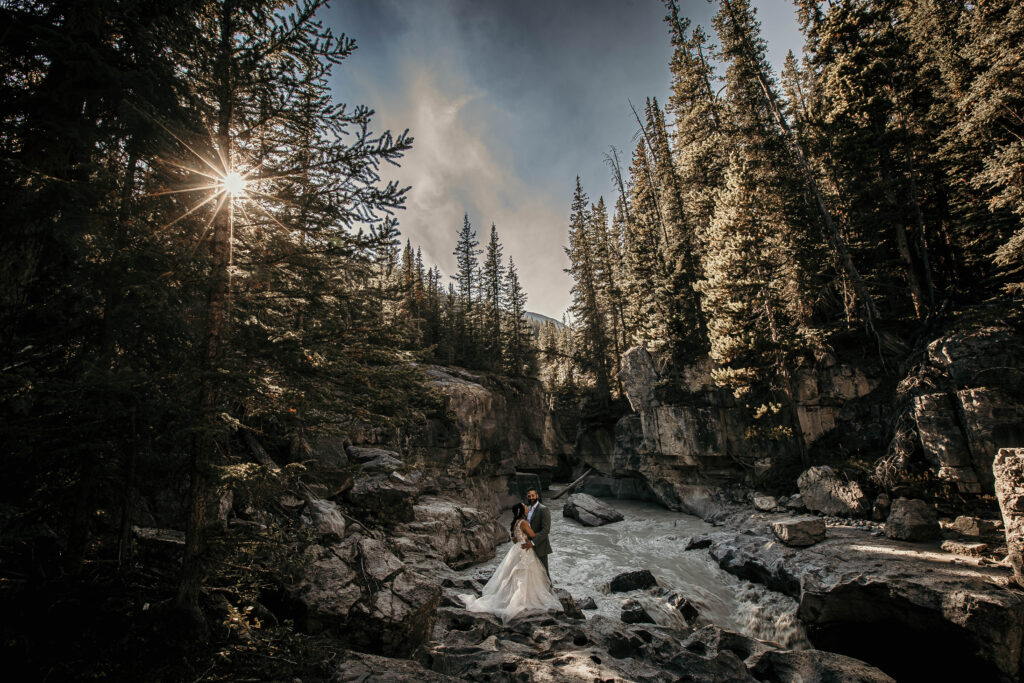 Couple eloping at a forest waterfall on an sunny day in the Canadian Rockies.