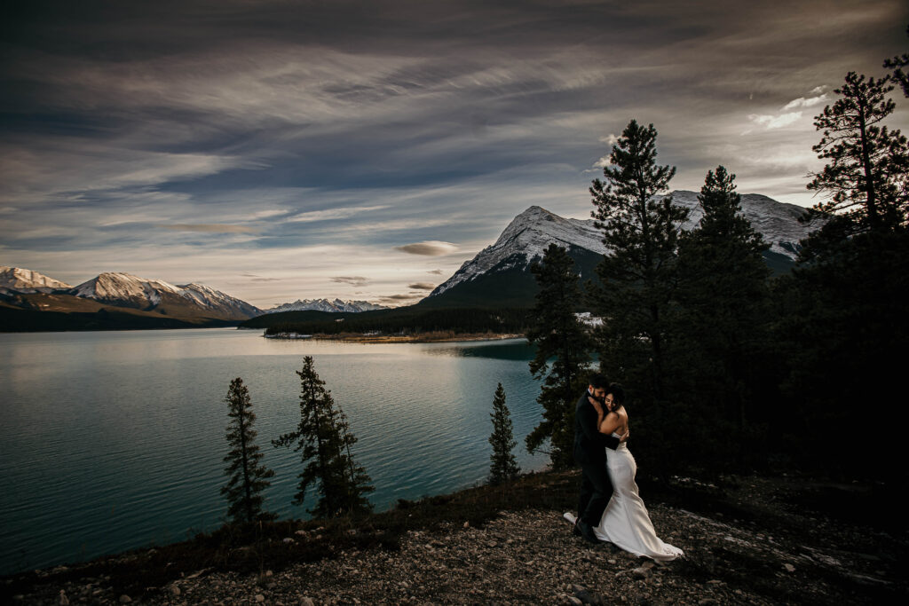Couple eloping at Abraham Lake known for frozen ice bubbles and snowy mountain scenery, but also stunning turquoise water and towering evergreens.