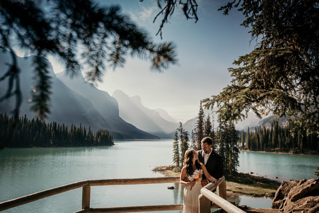 Couple eloping at Maligne Lake in Jasper National Park with emerald water and mountain peaks; spirit island in the background.