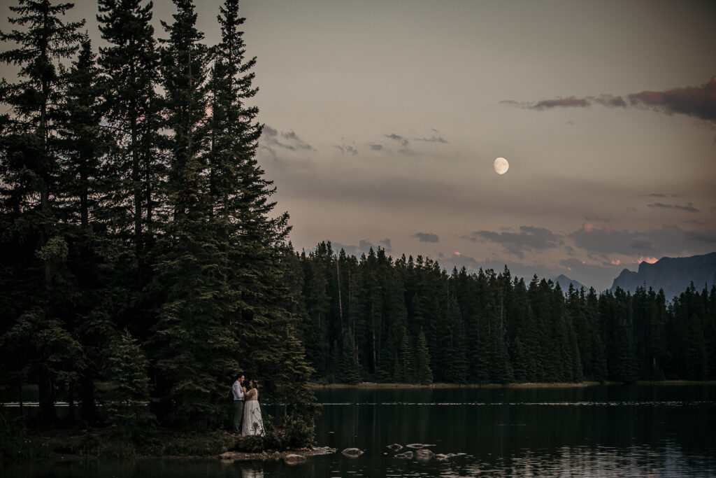Couple eloping at Two Jack Lake with calm water and mountain reflections near Banff.
