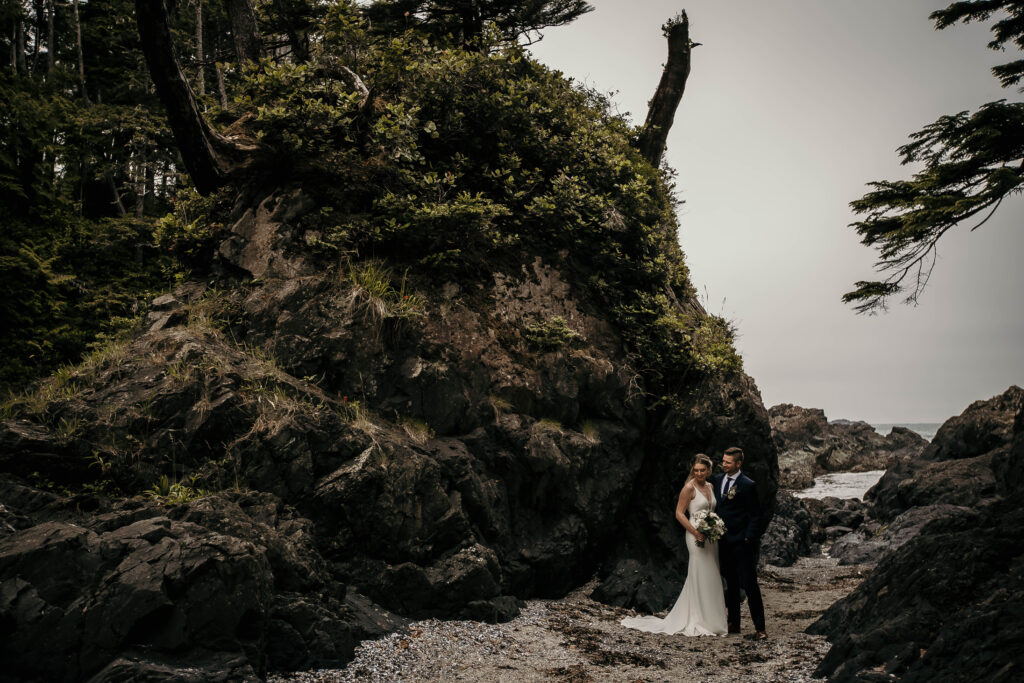 Couple exchanging vows on Brown’s Beach in Ucluelet with forested coastline.