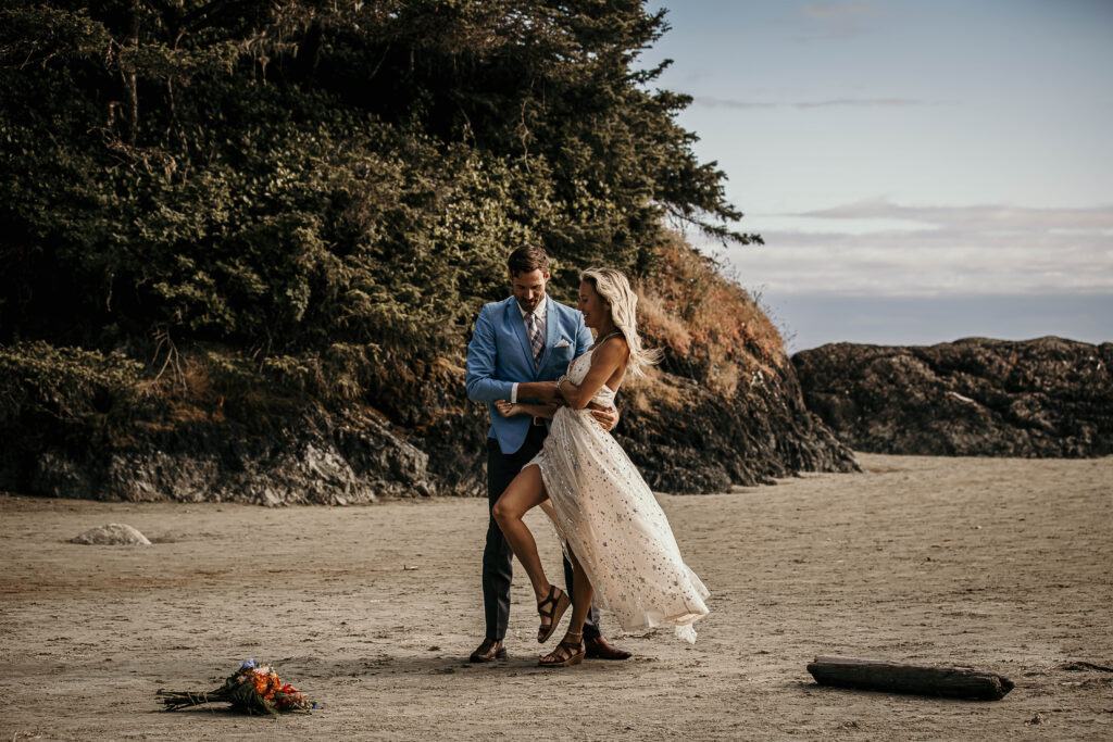 Couple eloping on Long Beach in Tofino with expansive ocean waves and sandy shoreline.